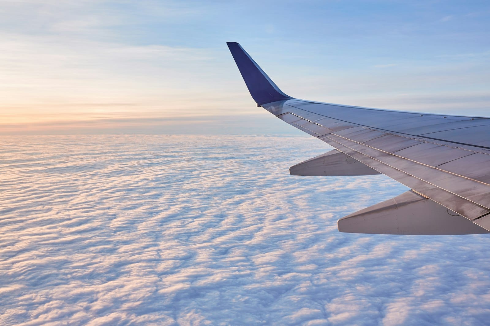 An airplane wing above the clouds at sunrise