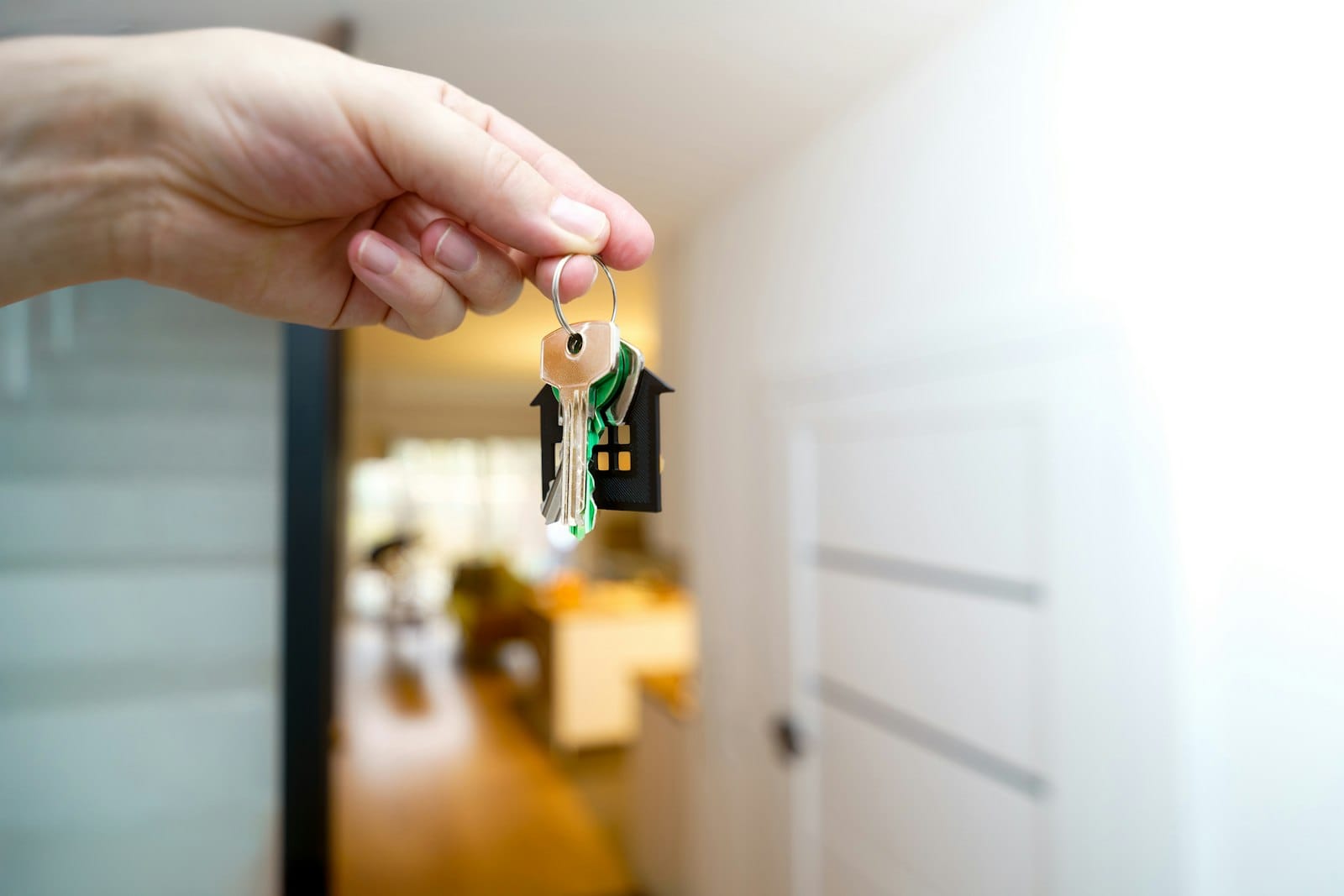 A hand holding house keys at an open front door